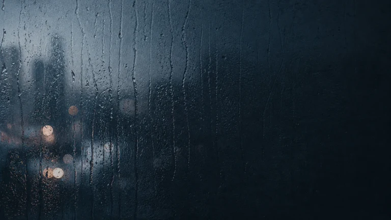 雨水覆盖的窗外亮着模糊的城市灯光